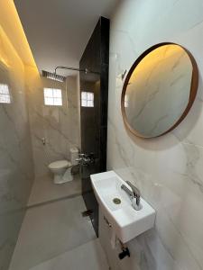 W białej łazience znajduje się umywalka i lustro. w obiekcie Bamboosa w mieście Bukittinggi