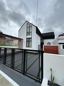 una casa blanca con una valla negra en Bamboosa, en Bukittinggi