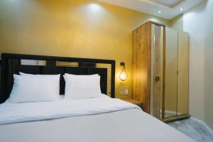 - une chambre avec un lit doté de draps blancs et d'une porte en verre dans l'établissement Steps Batumi - One Bedroom corner unit ocean view, à Batoumi