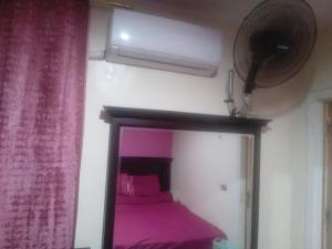 a bedroom with a bed with pink sheets and a fan at شقه مفروشه فرش فندقي بمدينه العبور الحي الراقي فيو حديقه in ‘Ezbet el-Insha