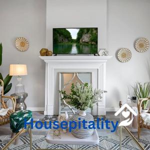 Housepitality - The Olive - 4 BR 2 Bath في كولومبوس: غرفة معيشة مع موقد وتلفزيون فوقها