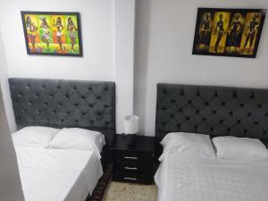 2 camas en una habitación de hotel con 2 colchas en Apartamentos cerca ala basílica, en Buga