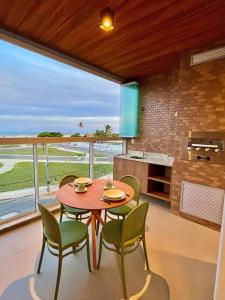 a table and chairs in a room with a large window at Solare - loft luxuoso de frente para o mar in Aracaju