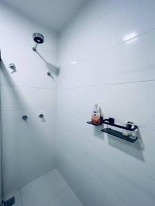 a white bathroom with a shower and a glass shower at Solare - loft luxuoso de frente para o mar in Aracaju