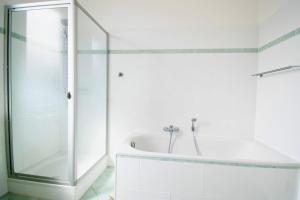La salle de bains blanche est pourvue d'une douche et d'une baignoire. dans l'établissement Villa Wilhelma Strandallee 146 Villa Wilhelma Apartment 3, à Timmendorfer Strand
