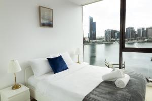 a bedroom with a large white bed and a large window at Pars Apartments - Collins Wharf Waterfront, Docklands in Melbourne