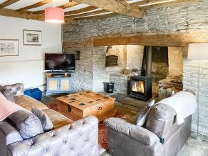 a living room with couches and a stone fireplace at Lower Farm in Llanfihangel Rhydithon