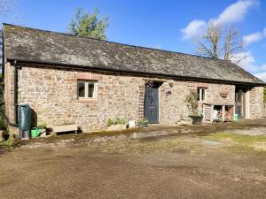 an old stone building with a black door at Tarka in Meeth