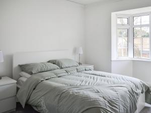 a white bedroom with a bed and a window at Sunny Bungalow in Chapel Saint Leonards