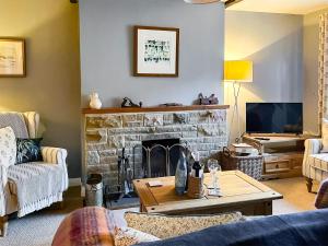 a living room with a fireplace and a tv at Half Moon Cottage in Brafferton
