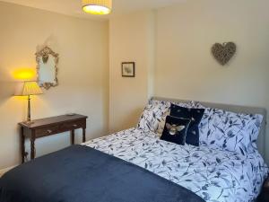 um quarto com uma cama com lençóis azuis e uma mesa em Half Moon Cottage em Brafferton