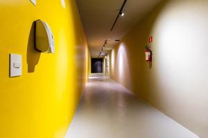 a hallway with a yellow wall and a yellow wall at Gracioso Studio no Brás com Piscina/Metrô Brás in Sao Paulo