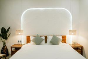 a bedroom with a large white bed with two lamps at Nagi cottage in Kinh Dinh