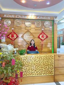 een vrouw achter een toonbank met klokken aan de muur bij Kim Hoàn Hotel Phan Rang in Phan Rang