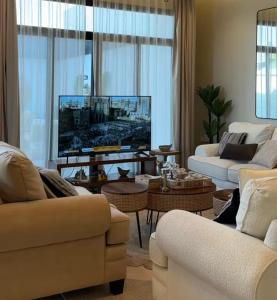sala de estar con 2 sofás y TV de pantalla plana en شاليه مُهرة, en Al Khabrāʼ