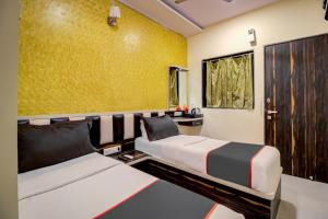 a bedroom with two beds and a yellow wall at Golden Tulipz Boutique in Mumbai