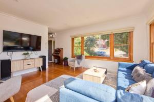 a living room with a blue couch and a tv at Basin Road Townhouse in Royal Park