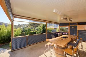 a large screened in porch with a wooden table and chairs at Basin Road Guesthouse in Royal Park