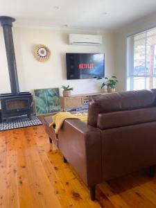 - un salon avec un canapé en cuir et une cheminée dans l'établissement OAK FLATS - Cosy Getaway, à Lake Illawarra