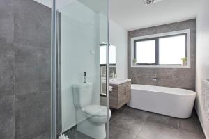 a bathroom with a toilet and a tub and a sink at The Gorge Townhouse, stunning home & location! in Royal Park