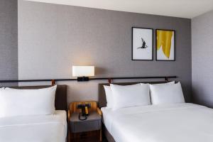2 bedden in een hotelkamer met witte kussens bij voco Chiayi, an IHG Hotel in Chiayi City