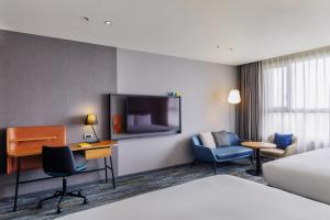嘉义市voco Chiayi by IHG的一间带床、书桌和电视的酒店房间