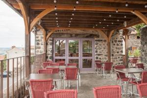 a patio with tables and chairs on a balcony at Auberge De Margot in Usson