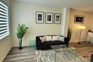 sala de estar con sofá negro y mesa de cristal en Modern entire 3 bedroom home in downtown Edmonton, en Edmonton