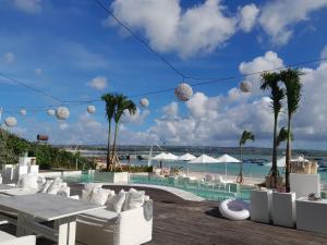 un complejo con piscina y playa con palmeras en Pronoia Beach Resort en Jimbaran