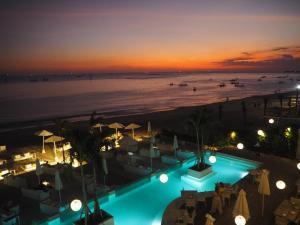 a view of a beach at night with a swimming pool at Pronoia Beach Resort in Jimbaran