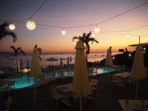 un restaurante con vistas a la playa al atardecer en Pronoia Beach Resort, en Jimbaran