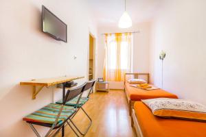 a room with two beds and a desk and a tv at Old Town Room Pula in Pula