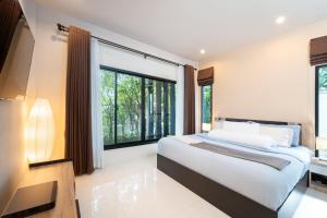 a bedroom with a bed and a large window at Baan Promphan Premium in Phuket Town