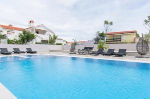 a swimming pool with lounge chairs next to a house at Villa Sana in Vir
