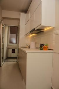 uma cozinha com armários brancos e um lavatório em Apartment Venera A&M em Šabac