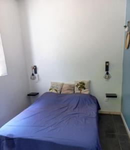 ein Schlafzimmer mit einem blauen Bett in einer weißen Wand in der Unterkunft Tropi Kay' Location - Bungalow avec jacuzzi in Le Diamant