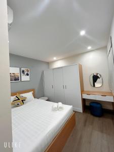 1 dormitorio con 1 cama blanca grande y espejo en Asahi Luxstay - FLC Green Home Pham Hung 2Br Apartment, en Hanói