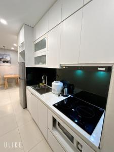 cocina con armarios blancos y fogones en Asahi Luxstay - FLC Green Home Pham Hung 2Br Apartment, en Hanói