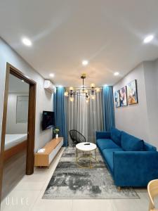 sala de estar con sofá azul y dormitorio en Asahi Luxstay - FLC Green Home Pham Hung 2Br Apartment, en Hanói