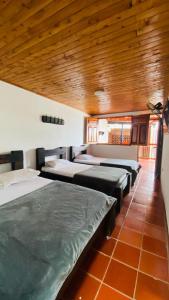 Habitación con 4 camas y techo de madera. en FINCA HOTEL JARDIN CAFETERO DEL QUINDIO, en Quimbaya