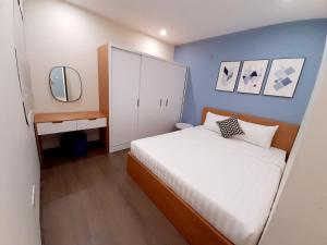 Un pequeño dormitorio con una cama blanca y una pared azul en Asahi Luxstay - FLC Green Home Pham Hung 2Br Apartment, en Hanói