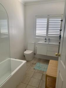 a bathroom with a toilet and a tub and a sink at Life's A Beach in Manyana