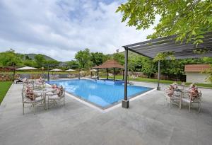 eine Terrasse mit einem Pool, Tischen und Stühlen in der Unterkunft The Hunting Lodge Resort Udaipur - Villas & Pool in Dabok