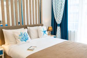 Seagull Beachfront Boutique Hotel في باتومي: غرفة نوم بسرير كبير مع ستائر زرقاء
