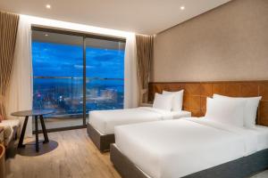 トゥイホアにあるApec Mandala Sun-Condotel Phu Yenのベッド2台、テーブル、窓が備わるホテルルームです。
