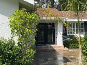 a white house with a black door and trees at Guest house with private entry and large pool in Los Angeles
