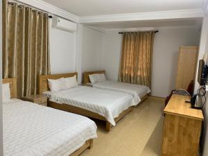 a hotel room with two beds and a television at Quynh Yen Hotel in Ha Long