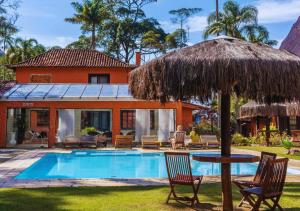 una casa con piscina y sombrilla de paja en Kastel Pedra Bonita, en Petrópolis