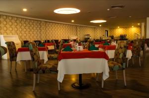 un comedor con mesas y sillas rojas y blancas en Orbi Hotel City Batumi, en Batumi