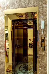 a glass elevator in a building with a man sitting on a chair at Tân Hiệp Hotel in Bùi Tiếng